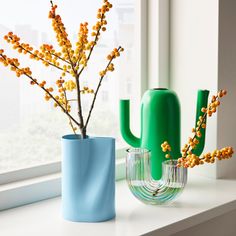 two vases sitting on a window sill next to each other with flowers in them