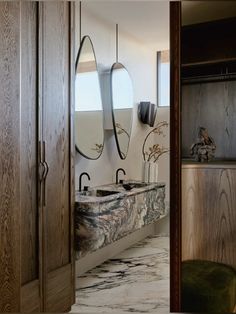 a bathroom with marble counter tops and two mirrors on the wall next to each other