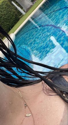 the back of a woman's head next to a swimming pool with long black hair