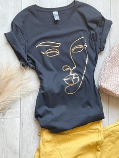 Description 100% cotton t-shirt. Black shirt with graphic outlined in gold. True to size. Sizes Women (S-XL) Neckline Options:  Crew or V-neck Processing This product will be created and shipped within 5-7 business days. Be sure to check out my other creations at www.canvasandcreationsus.etsy.com Trendy Gold T-shirt For Summer, Trendy Gold Summer T-shirt, Trendy Gold Crew Neck T-shirt, Gold Graphic Tee With Screen Print, Gold Screen Print Graphic Tee Tops, Gold Crew Neck Top With Screen Print, Gold Screen Print Graphic Tee, Gold Short Sleeve Tops With Graphic Print, Gold Graphic Print Short Sleeve Top