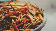 a bowl filled with lots of red and yellow hot chili peppers on top of each other