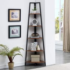 a corner shelf in the corner of a room with pictures on the wall and a potted plant next to it