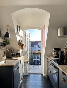 a woman standing in a kitchen next to an open door that leads into a balcony