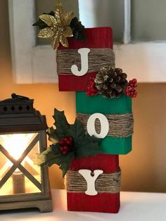 a wooden block with the word joy decorated on it next to a lit candle holder