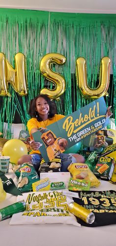 a woman sitting on top of a bed surrounded by balloons and confetti in the shape of letters