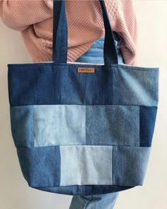 a woman is holding a blue bag with patchwork on the front and back sides