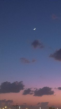 an airplane is flying in the sky at night with clouds and lights behind it as the sun sets