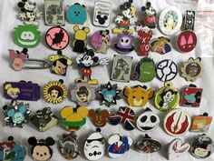 many different disney pins and badges on a white sheet