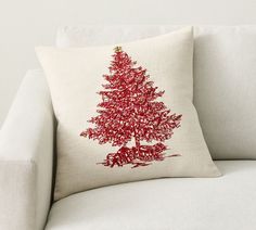 a white couch with a red christmas tree pillow on it's back and side