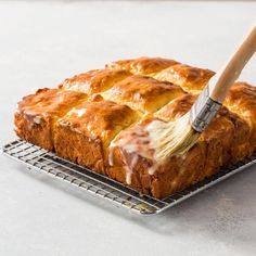 a person using a brush to spread icing on a loaf of bread