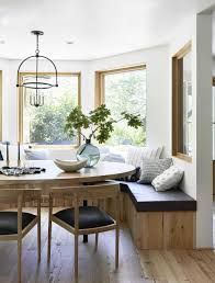 a dining room table surrounded by chairs and benches with windows in the back ground area