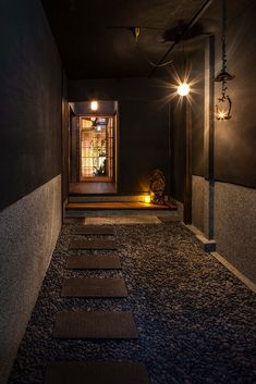 a dimly lit hallway with steps leading up to the door and lights on either side