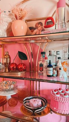 a shelf filled with cakes and desserts on top of glass shelves in a pink room