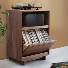 an old record player is sitting on top of a wooden cabinet with records in it