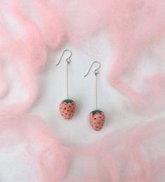 two strawberry shaped earrings on top of a pink background