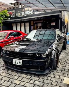 two cars parked next to each other in front of a building on a brick road