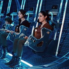 three women sitting on seats in a futuristic space station