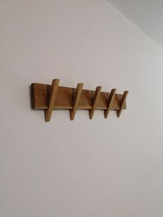 a wooden coat rack on the wall next to a white wall with three hooks hanging from it's sides