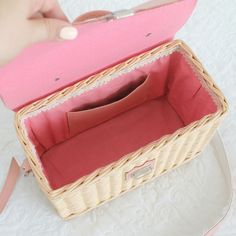 a person is holding a pink purse on a white table with a handbag in it