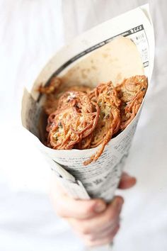 a person is holding some kind of food in a paper wrapper and it looks like onion rings