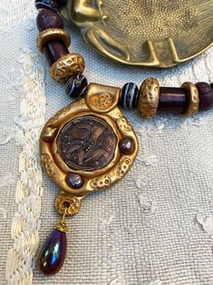 A beautiful Bohemian Czech glass button with copper lace encrusted in a golden polymer pendant, Byzantium style + river pearl cabochons! Beautiful large Murano beads and mauve and old gold polymer... Be unique! Each jewel only exists in one copy and you will be the only one to wear it. Pendant: I looked for a Byzantine style with the textured old gold polymer that encircles the wonderful Czech button. The 3 small purple river bead cabochons also go with this style. Finally, a pretty purple iride Copper Lace, River Pearls, Vintage Pendant Necklace, Polymer Beads, Vintage Pendant, Glass Buttons, Jewelry Creation, Czech Glass, My Jewellery