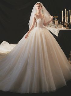 a woman in a wedding dress standing next to a table with candles and an elaborate veil