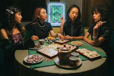 four women sitting around a table with food on it