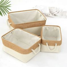 three white and tan baskets sitting on top of a table next to a palm tree