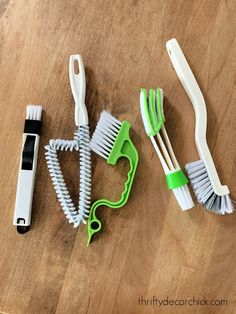 three toothbrushes, one green and one white on a wooden table with scissors