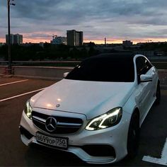 a white car parked in a parking lot with the sun setting on it's horizon