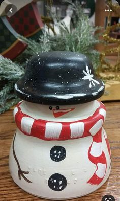 a ceramic snowman with a hat and scarf on it's head sitting on a table