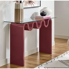 a red console table with a glass top and wavy lines on the edge, in front of a white wall