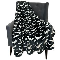 a black and white blanket sitting on top of a chair next to a gray chair