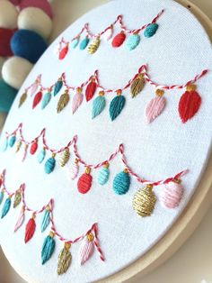 a close up of a embroidery on a white board with ornaments hanging from the hoop