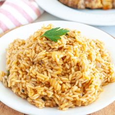 two plates filled with rice and meat on top of a wooden table next to another plate