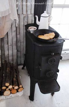 an old fashioned stove with some food on it next to a tea pot and mug