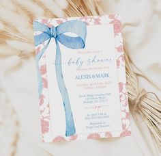 a baby shower card with a blue bow on it's front and pink flowers in the back