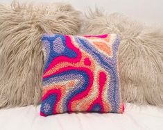 a close up of a pillow on a bed with a white furnishing behind it