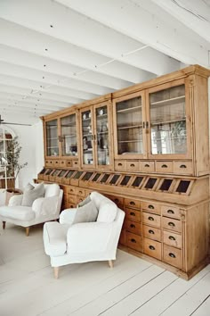 a living room filled with furniture and lots of wood cabinet space next to a white couch