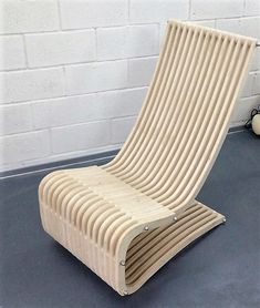 a wooden chair sitting on top of a floor next to a white brick wall in an empty room