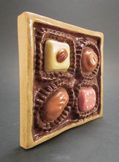 a chocolate box with four different types of candies in the center, on a gray surface