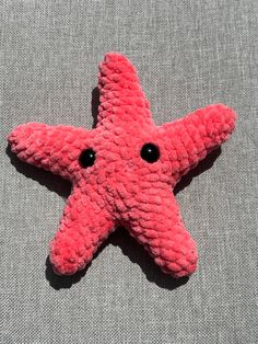 a pink starfish laying on top of a gray surface