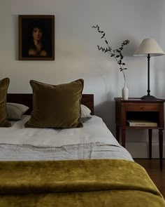 a bedroom with a bed, two lamps and a painting on the wall above it