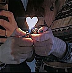 a person holding a smart phone in their hands with a heart shaped light on it