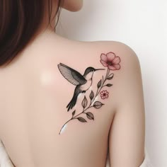 the back of a woman's shoulder with a hummingbird and flowers on it