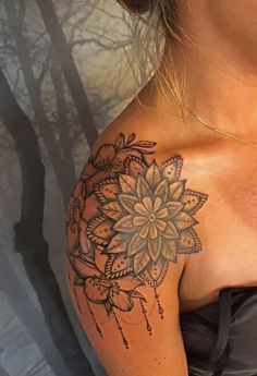 a woman's shoulder with a tattoo on it, and an intricate flower design