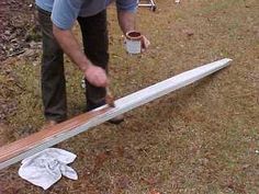 a man is bending over to pick up something from the ground while holding a surfboard