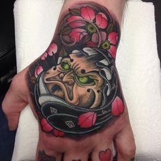 a hand with a tattoo on it that has an image of a cat in a helmet