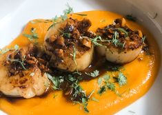 seared scallops with orange sauce and garnish on a white plate