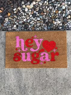 a door mat with the words hey sugar on it next to gravel and rocks that says hey sugar